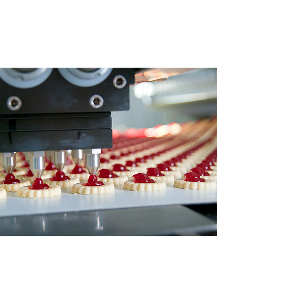 En automatisert maskin som påfører rød syltetøy på kjeks i en matproduksjonslinje.