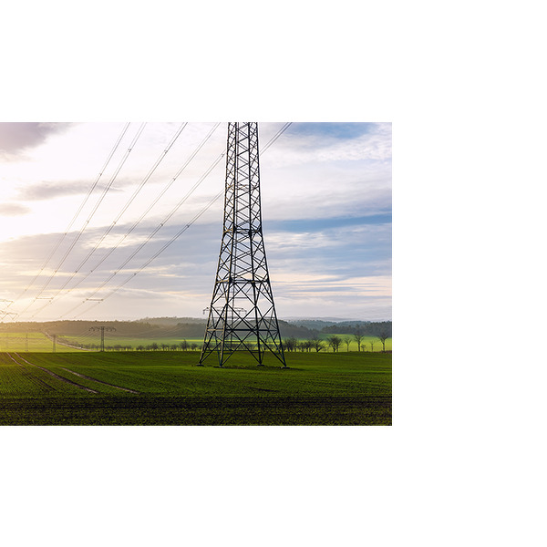 Høyspentledninger og kraftmaster som strekker seg over en grønn eng ved soloppgang.
